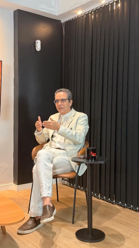 Maurício Rands gesticula durante entrevista, sentado em poltrona, de paletó claro